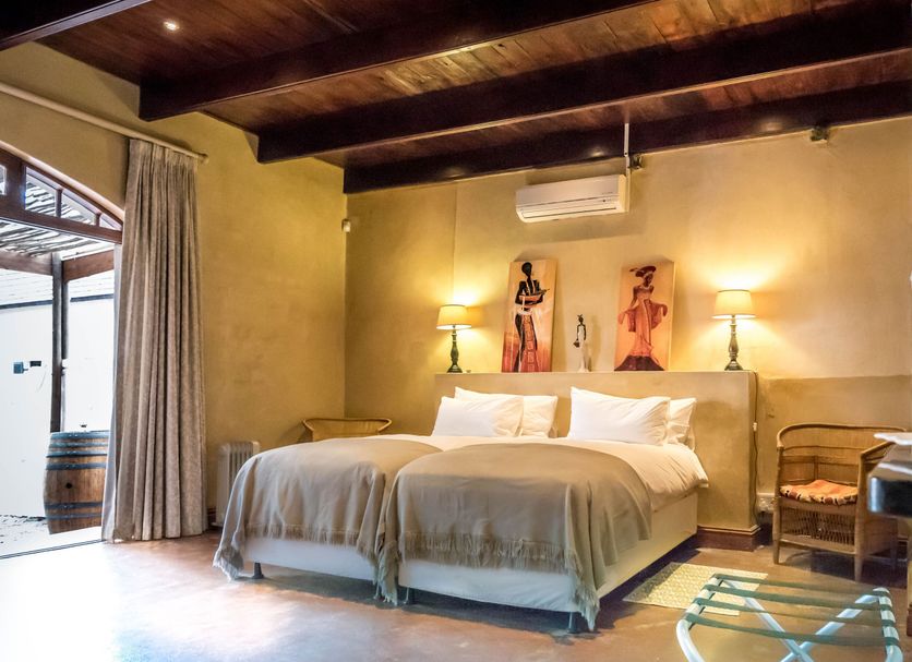 De Leeuwenhof Estate in Paarl: twin beds in a rustic guest room with wooden ceiling and courtyard door