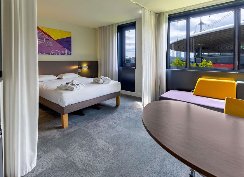 Novotel Suites Paris Stade de France room with bed, seating area, and large windows in Saint-Denis