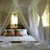 Nypa Style Resort Camiguin in Mambajao: canopy bed with sheer mosquito netting and towel swans