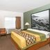 Super 8 by Wyndham Monterey room with double bed, desk, chair, TV, and large framed coastal photo