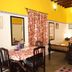 La Villa Creole Pondicherry guest room with four-poster bed, dining table and bright yellow walls