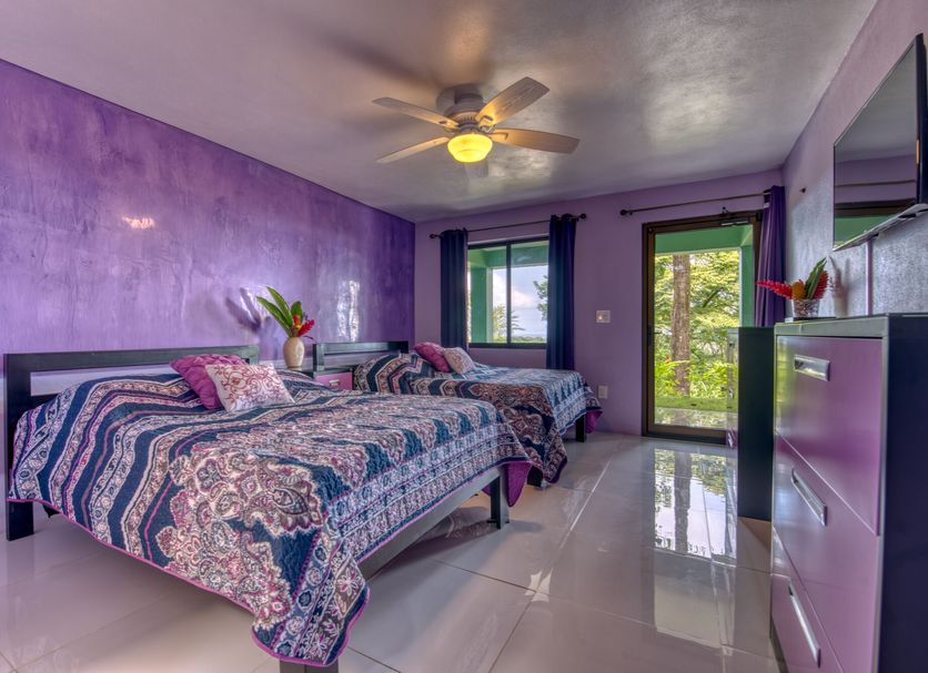 Casa Conley Del Mar in Hone Creek bedroom with two beds, purple walls, ceiling fan, and balcony doors