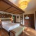 Melia Ba Vi Mountain Retreat guest room with canopy bed, warm wood finishes, and lounge bench in Ba Vi