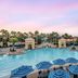 Hilton Grand Vacations Club Parc Soleil Orlando pool with umbrellas, palm trees and resort buildings in Orlando