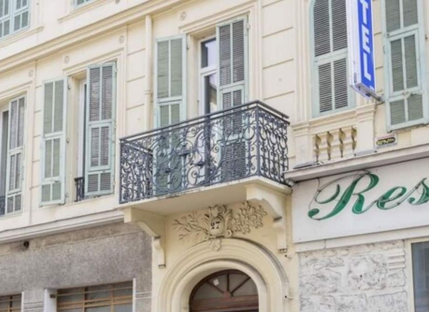 Le Pastoral hotel facade in Nice with ornate balcony and shuttered windows