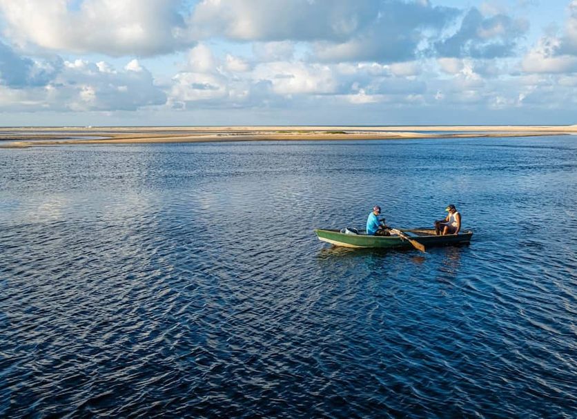 Pousada Villa do Sol in Natal, with two people in a canoe on calm blue water by the shore