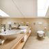 Familienhotel Mateera Gargellen bathroom with double sinks, wall-mounted toilet and glass shower