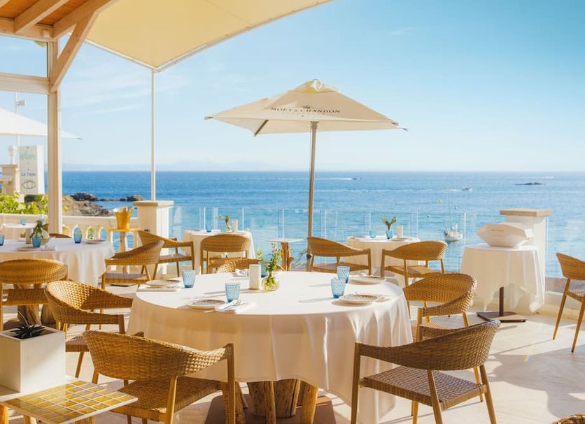 Hotel Vistabella in Roses: seaside terrace dining with tables, umbrellas and ocean views