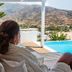 Guest lounging by infinity pool at Levantes Ios Boutique Hotel in Mylopotas, with beach and hills beyond