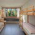 Grindelwald Youth Hostel bunk room with two sets of wooden bunk beds and a window mountain view
