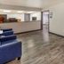 Baymont by Wyndham Laredo lobby with blue chairs, front desk window, and wood-look flooring in Laredo