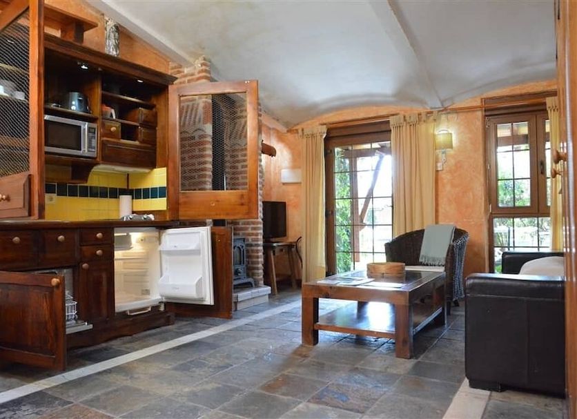 Hospedium Hacienda Las Cavas in Olmedo: rustic suite with kitchenette, seating area, and stone floor
