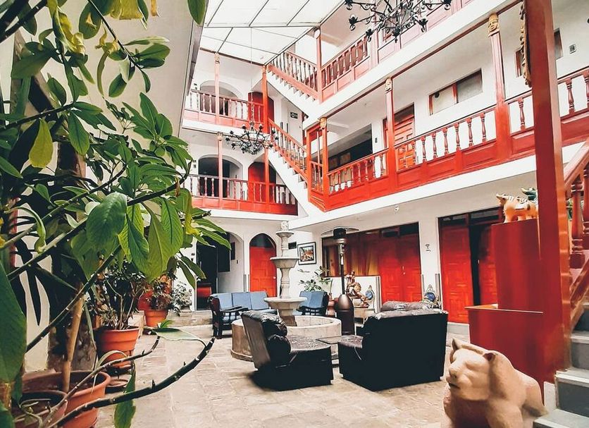 Hotel Choquequirao Cusco courtyard lounge with red balconies, seating, plants, and chandelier