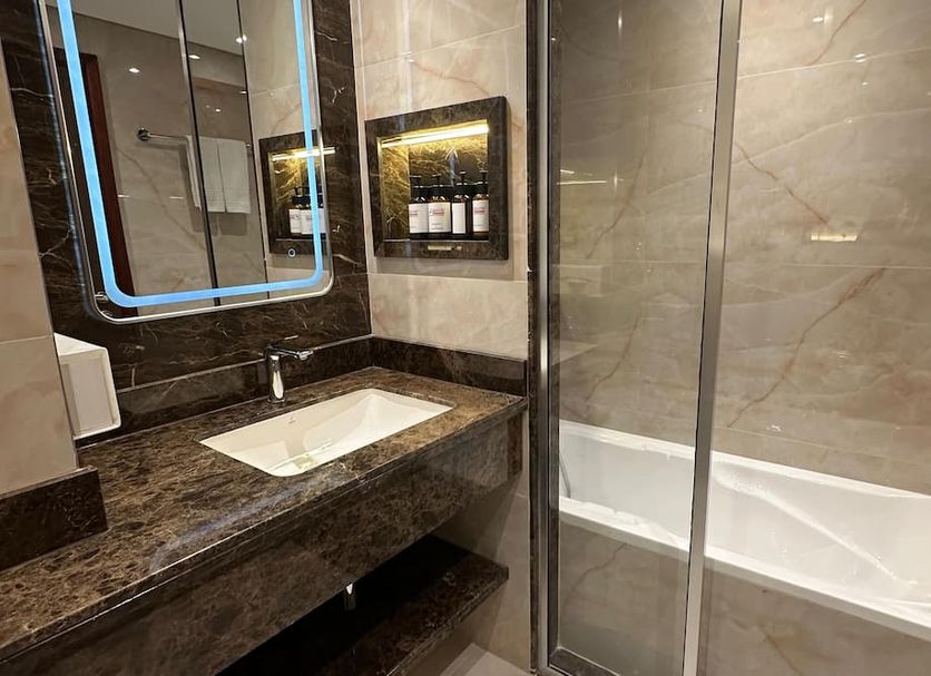 Dubai Grand Hotel by Fortune bathroom with marble vanity, mirror, and glass-enclosed bathtub in Dubai