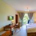 Lotos Inn & Suites, Nairobi guest room with king bed, desk, and balcony doors to greenery