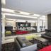 Mantra Melbourne Airport lobby lounge with black sofas, red ottoman, bar seating and abstract wall art