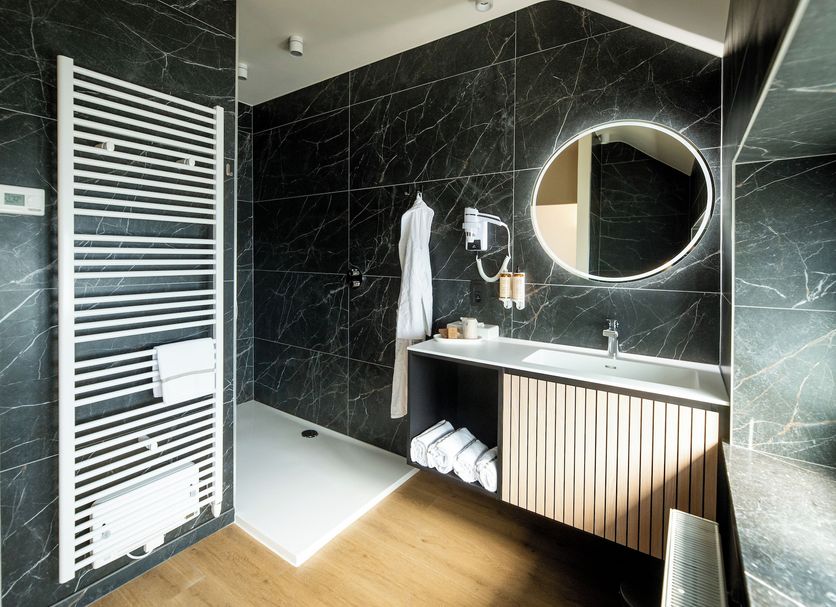 La Villa des Fleurs Spa bathroom with walk-in shower, round mirror and towel warmer