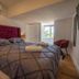 Winchelsea Lodge bedroom with tufted headboard, king bed, bedside lamp, chair, and window view