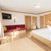Haus Sonnwend in Alpbach guest room with wooden bed, seating nook, and warm alpine-style interior