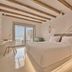 Balius Mykonos guest room with sea view, wood-beam ceiling, and minimalist bed in Mykonos