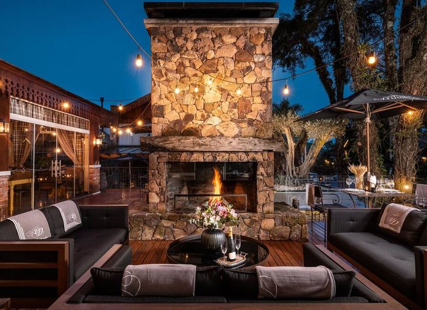 Hotel Valle Dincanto in Gramado: outdoor lounge with stone fireplace, seating, and string lights