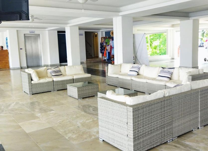 Hotel Aristos Acapulco lobby with wicker sofas, light tile floors, and open seating area