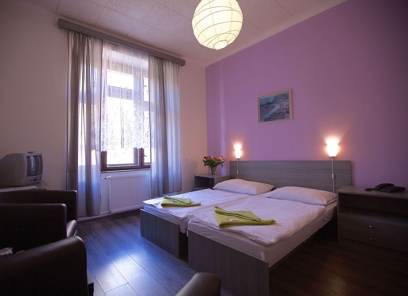 Hotel Olga Prague guest room with twin beds, purple walls, window and chairs