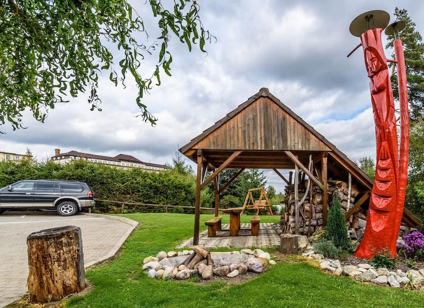 Hotel Villa Siesta in Vysoké Tatry, rustic outdoor seating area with fire pit and tall red sculpture