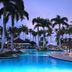 Bahia Principe Explore La Romana poolside at dusk with palm trees and lounge chairs