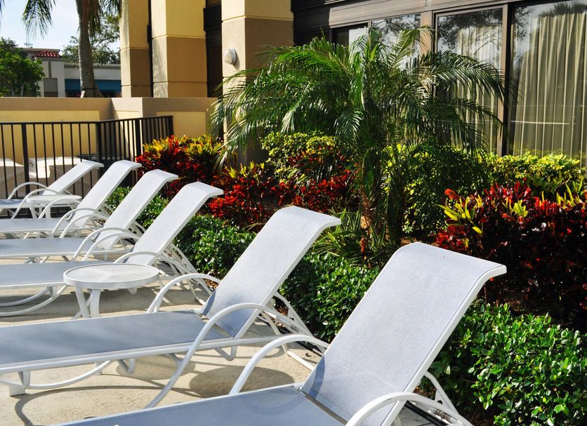 Holiday Inn Express Boca Raton-West by IHG poolside lounge chairs amid tropical landscaping