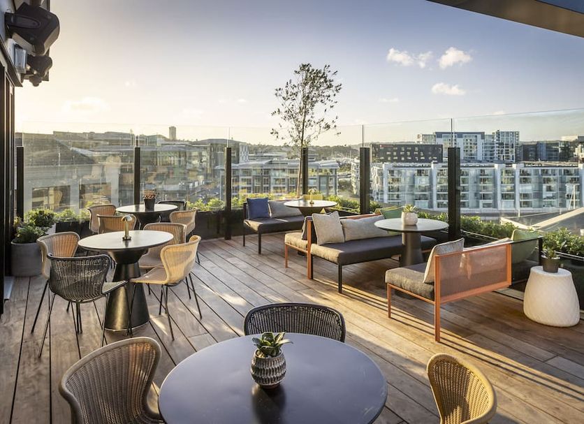 QT Auckland rooftop terrace with city skyline views, lounge seating and tables in Auckland