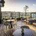 QT Auckland rooftop terrace with city skyline views, lounge seating and tables in Auckland