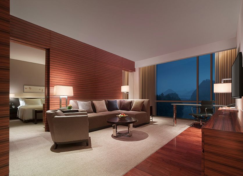 New World Guiyang Hotel suite with mountain view, sofa, desk and large floor-to-ceiling window