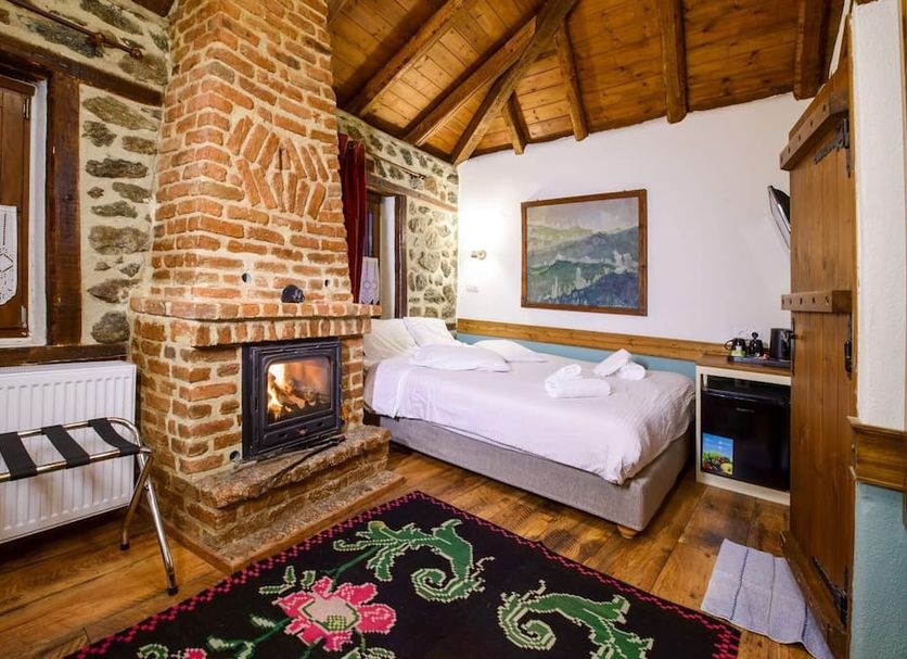 Agios Germanos hotel room with stone fireplace, wood-beamed ceiling, twin beds and mountain-view painting