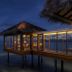 The Residence Maldives, Falhumaafushi: overwater villa at dusk with ocean views and lit interior