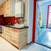 Pal's Mini Hostel in Budapest kitchenette with light wood cabinets, red backsplash, and adjoining blue room