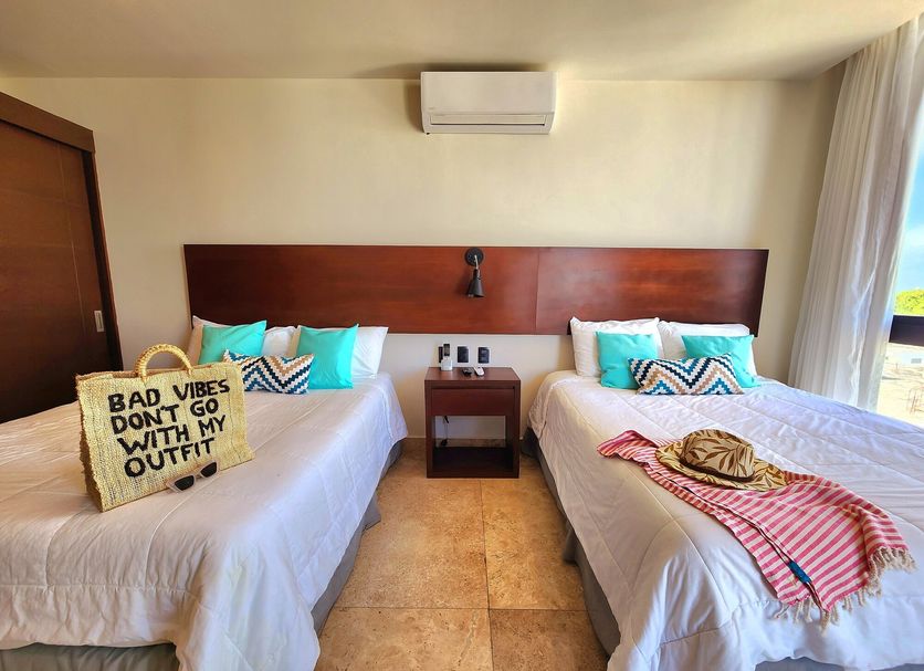 Meliora By Bunik in Playa del Carmen: twin beds with pillows, bedside table, and ocean-view window