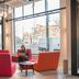 Conscious Hotel The Tire Station in Amsterdam lobby seating area with colorful chairs and large windows