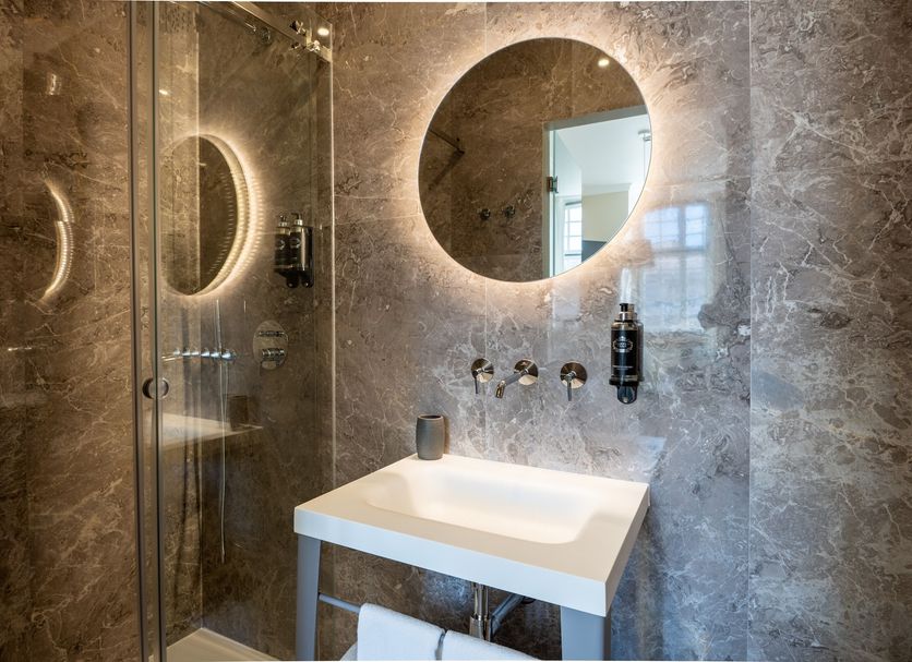 Boemio Flh Hotels Lisbon bathroom with round backlit mirror, shower glass, and floating sink