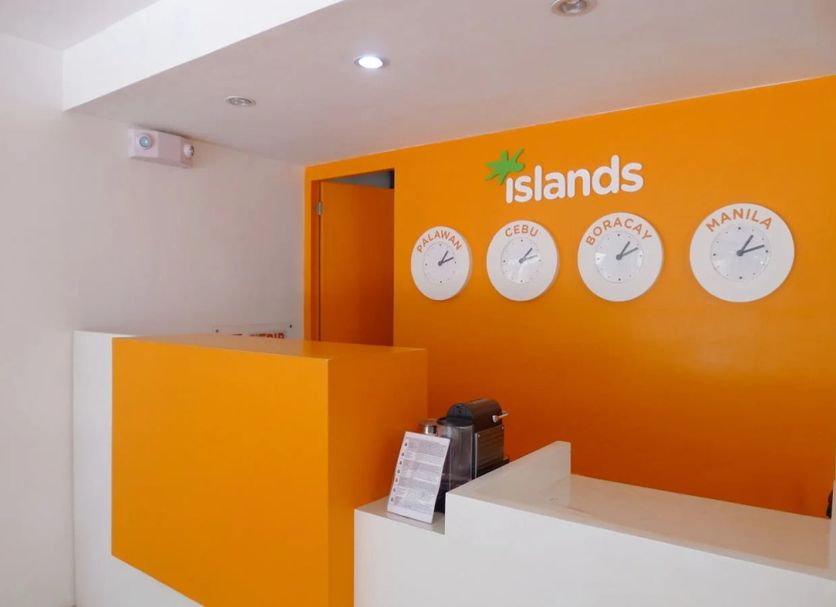 Islands Stay Hotels - Puerto Princesa reception desk with orange wall and island clocks