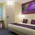 Comfort Hotel Orleans Olivet Aulnaies guest room with two beds, desk, and purple wall art in Olivet