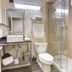 Bathroom at Guy Harvey Resort on Saint Augustine Beach with glass shower, toilet, sink and mirror