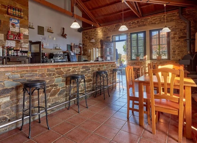 Hotel Rural Molino del Arriero in Luyego: rustic bar with stone counter, stools, and wooden dining tables