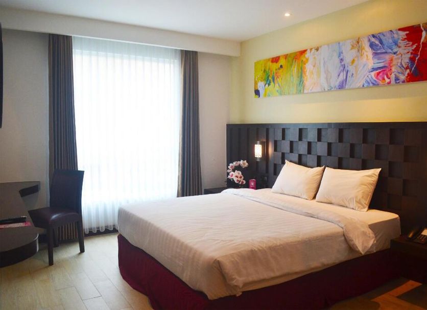 Grand Orchid Hotel Yogyakarta in Depok bedroom with king bed, large window and colorful wall art