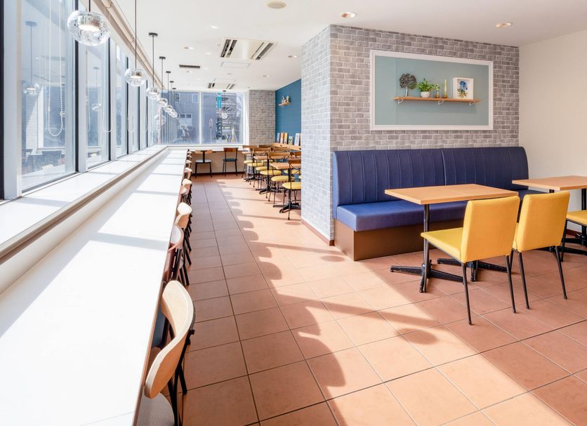 Comfort Hotel Narita in Narita lounge with blue banquette seating, yellow chairs, and floor-to-ceiling windows