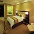 Shenyang Neu International Hotel room in Shenyang with king bed, lounge chair, and warm lighting