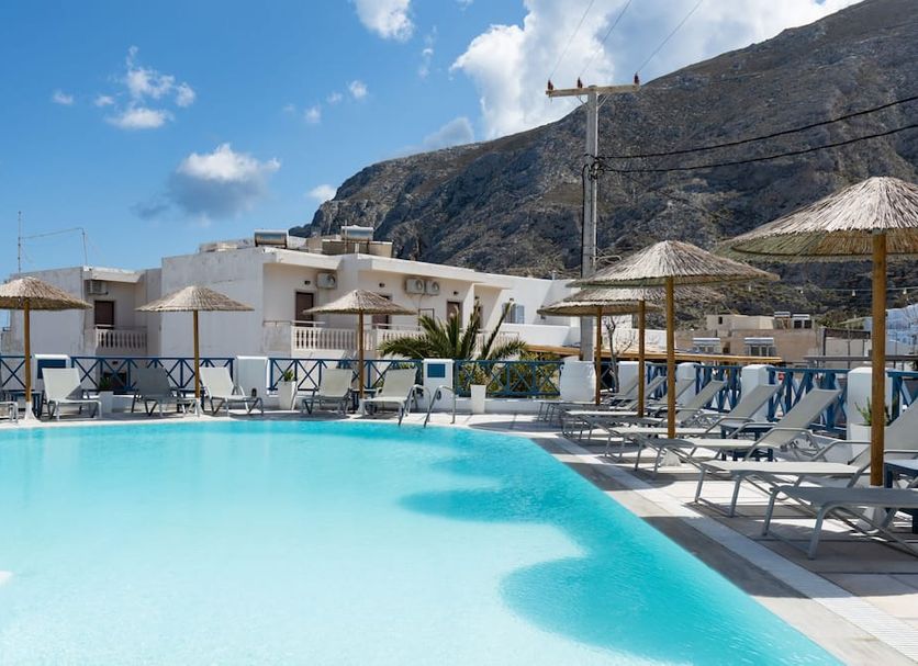 Hotel Sunshine in Kamari with a turquoise pool, sun loungers, and mountain backdrop