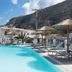 Hotel Sunshine in Kamari with a turquoise pool, sun loungers, and mountain backdrop