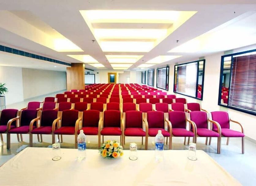 Hotel Airlink Castle in Neduvannoor conference hall with rows of red chairs and a front table