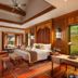 Anantara Xishuangbanna Resort bedroom with wood decor, canopy bed, desk and garden view